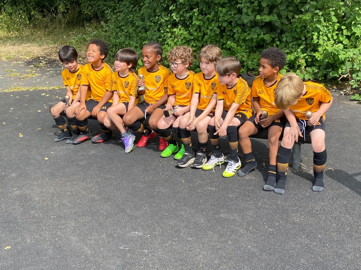 Young Chorlton Rovers players sitting together on a bench in club kit after a match